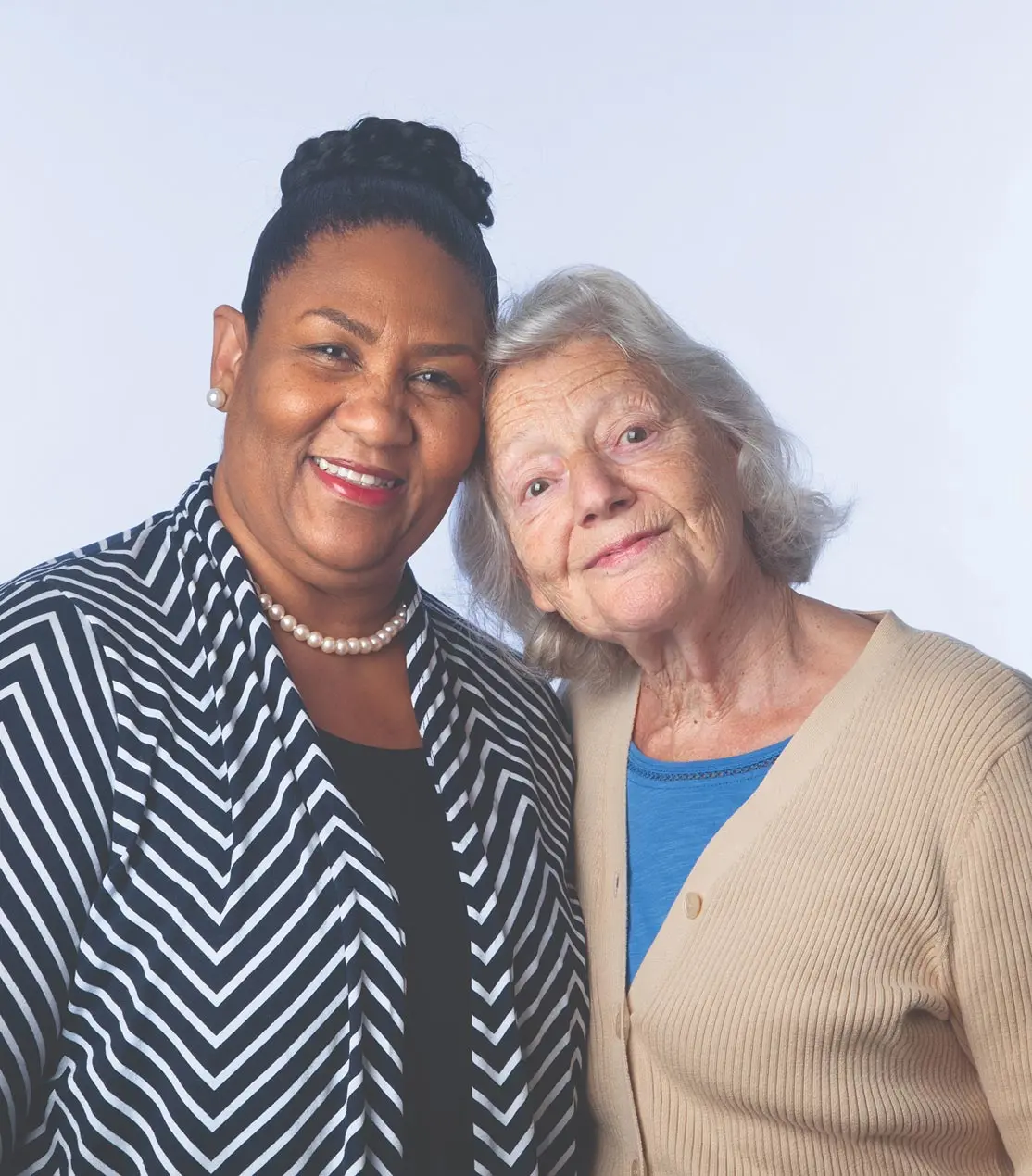 Two elderly friends, one Black and one white, embracing warmly.